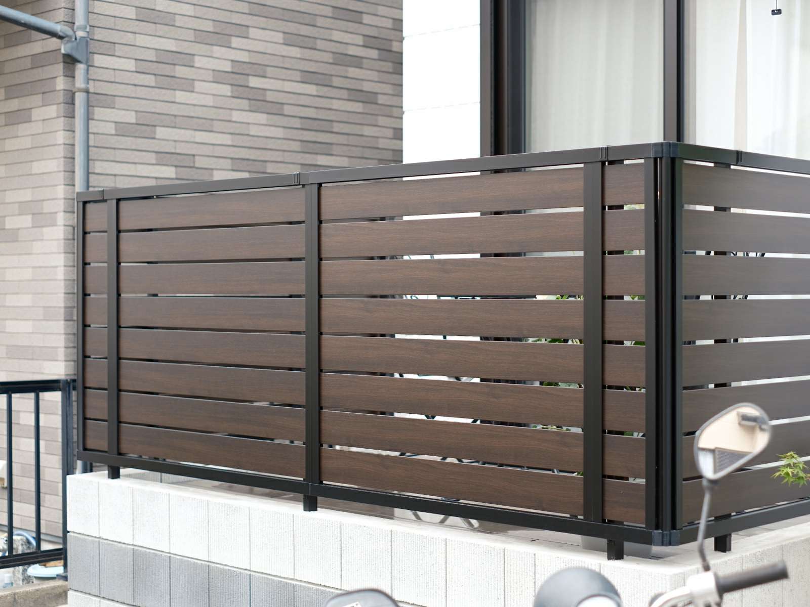 ウッドデッキ下のブロック囲いと木調アルミフェンスで目隠しされたウッドデッキ