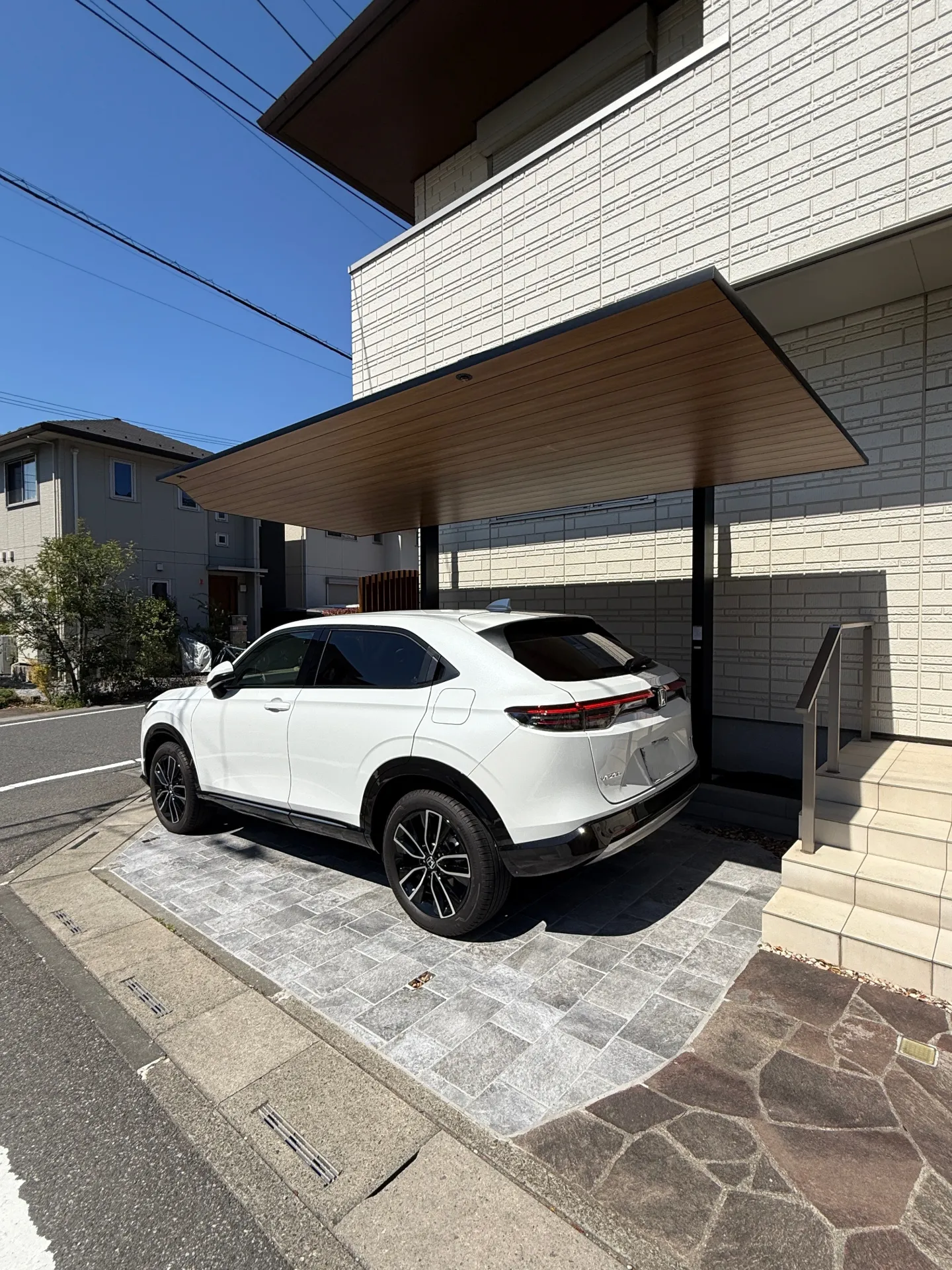 明るい色味のタイルと黒のカーポートSCがコントラストを生む、清潔感のあるカースペース全体像。