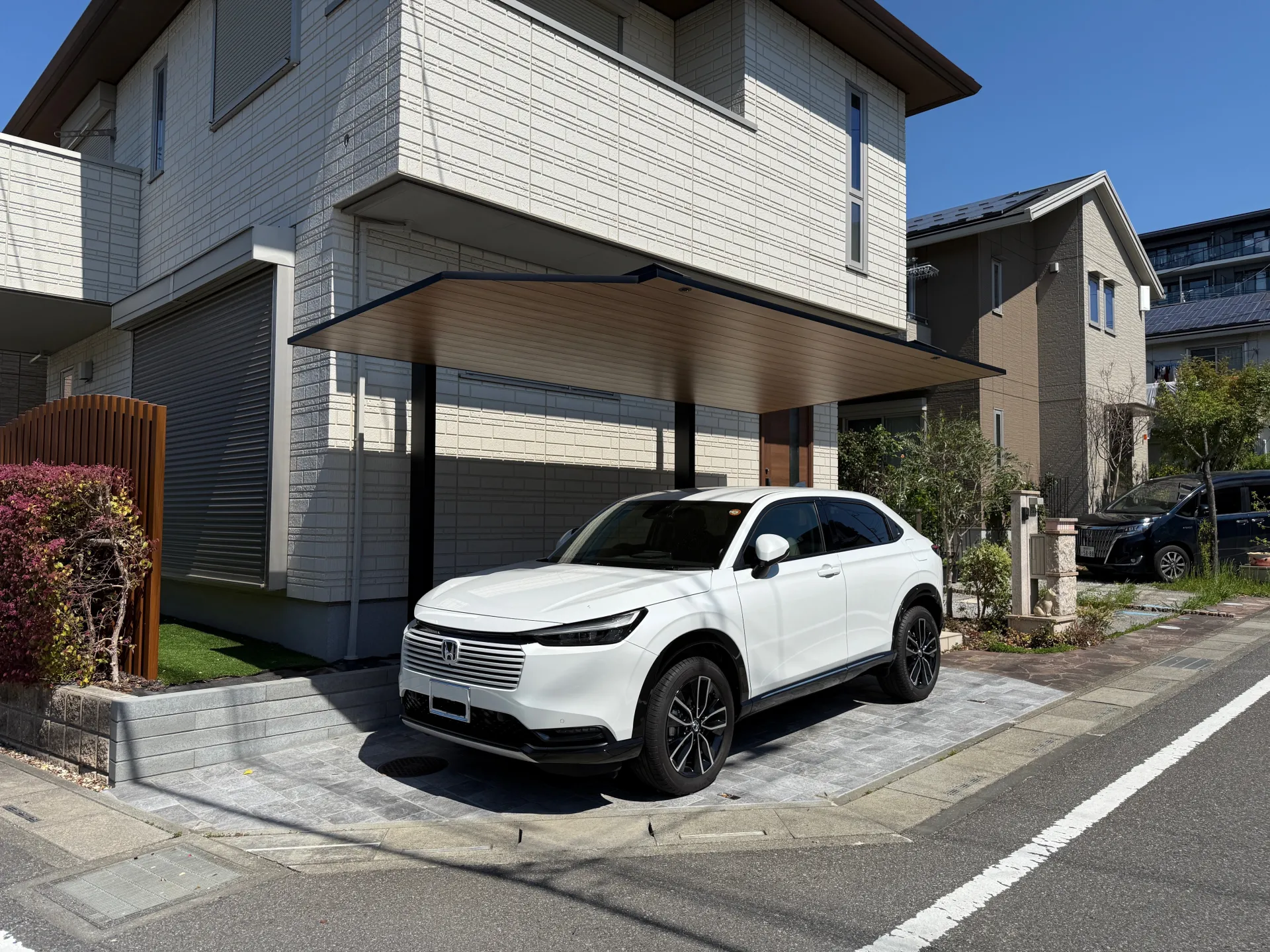 吉川市での駐車場リフォーム完成写真。LIXILのカーポートSCと、ミラタップの自然石調タイルが美しく調和したスタイリッシュな外構。