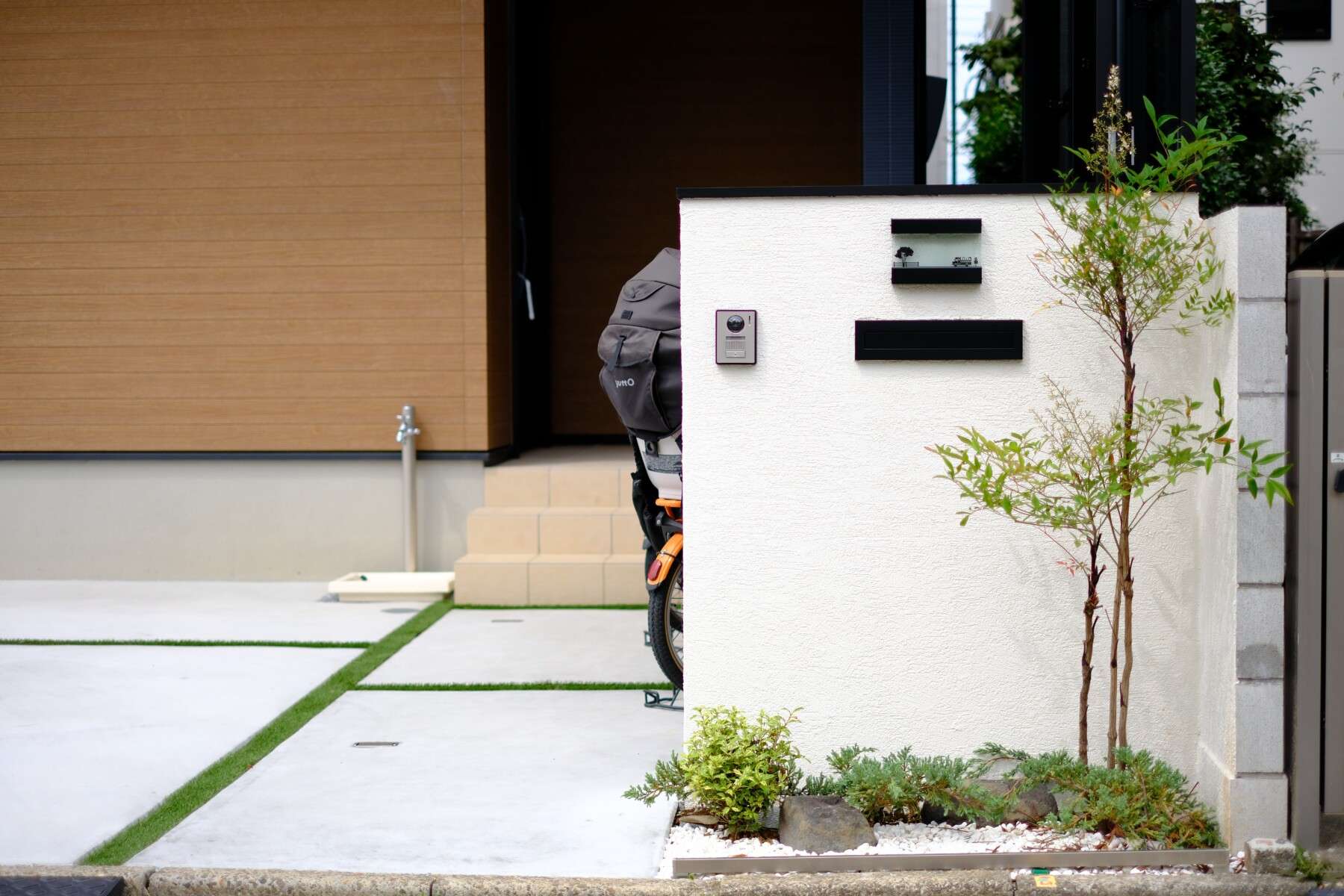 道路から少し下がった位置に設置したL字門柱と植栽でやわらかな印象を与える門まわり