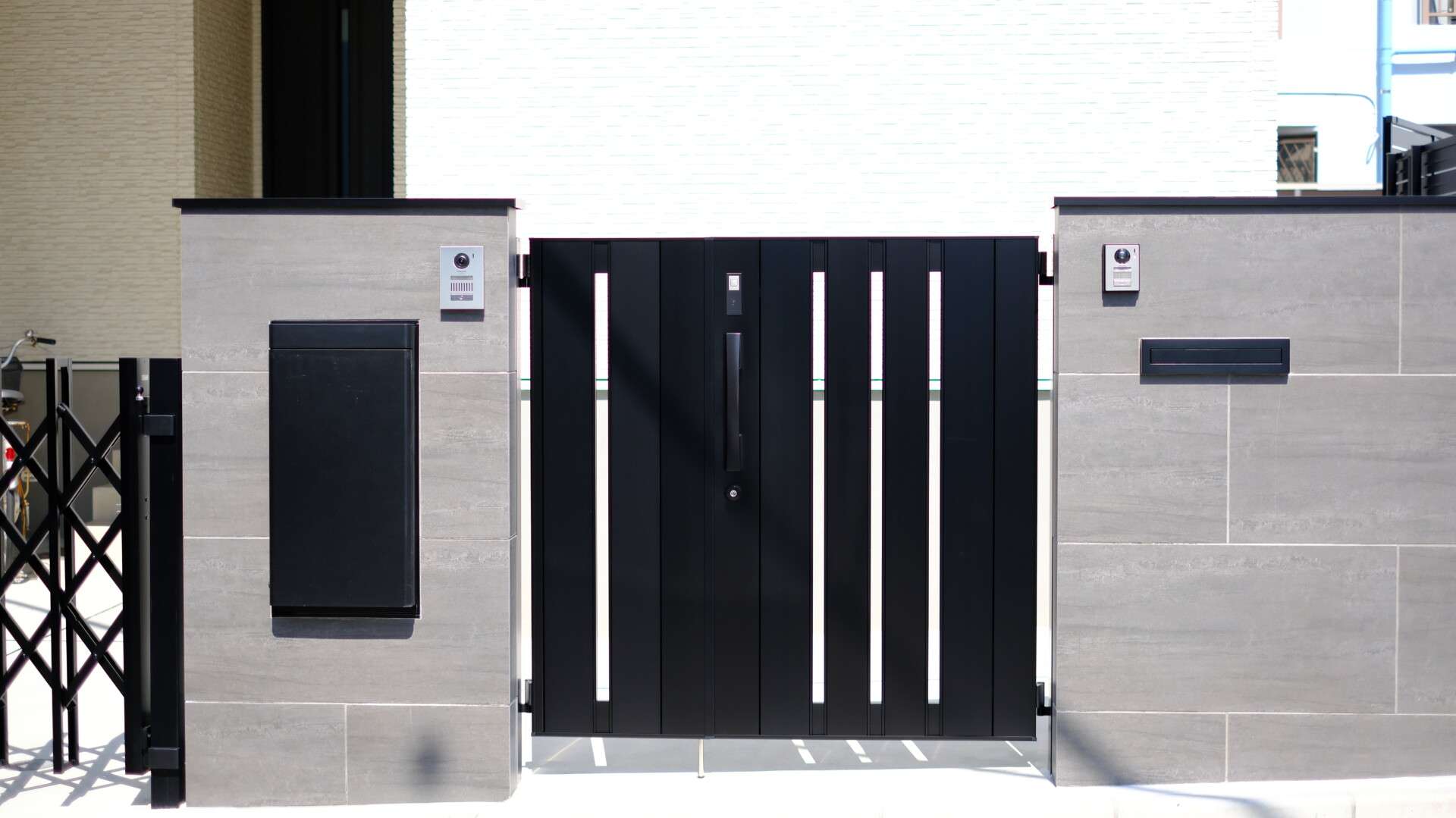 リビエラ製大判タイル（900×450mm）を使用した2世帯対応門柱のディテールとLIXILスマート宅配ボックスを門柱に組み込んだ様子。非対面受け取りに対応。