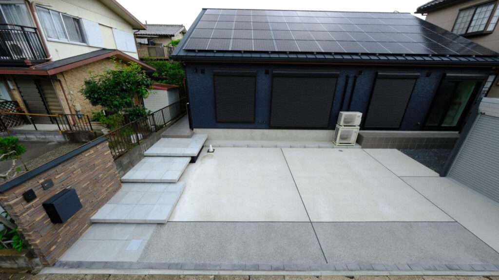 門柱とアプローチ全体を斜めから撮影。敷地と建物のバランスが分かる。