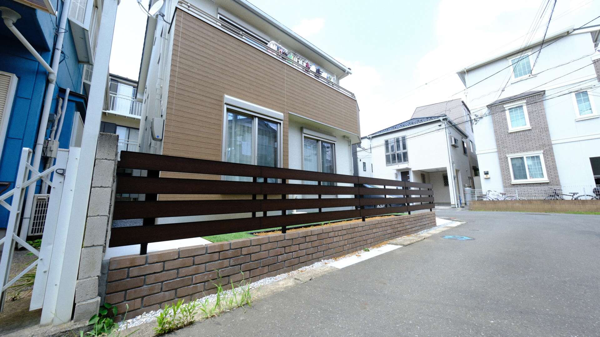 レンガの塀と木目調フェンスで囲われたローメンテナンスの庭（さいたま市）