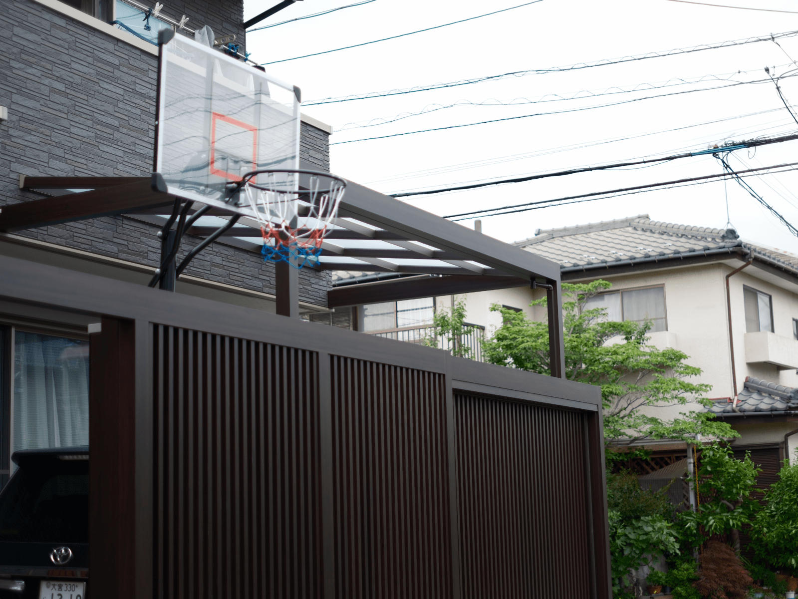 玄関前にGルーフとリニア吊り引き戸で車庫スペースと目隠しをしおしゃれに使い勝手を高めた写真。