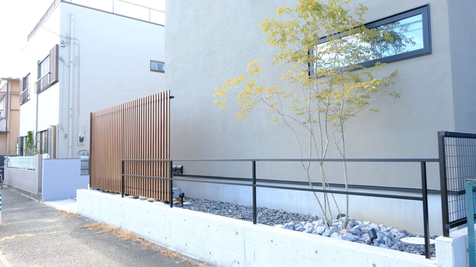 アルミフェンスと打ちっぱなし仕上げの土留めで構成された外構