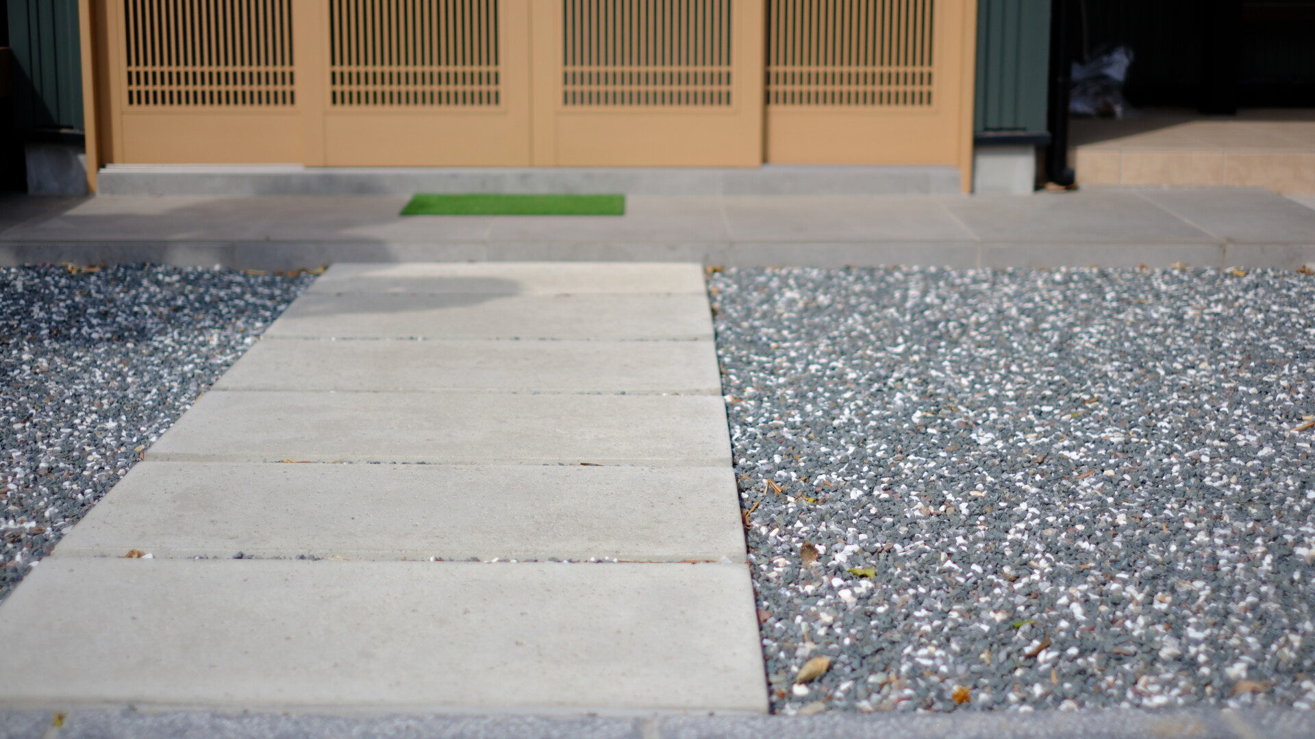 洗い出し仕上げと大谷石調の平板を組み合わせた和モダンな玄関前デザイン