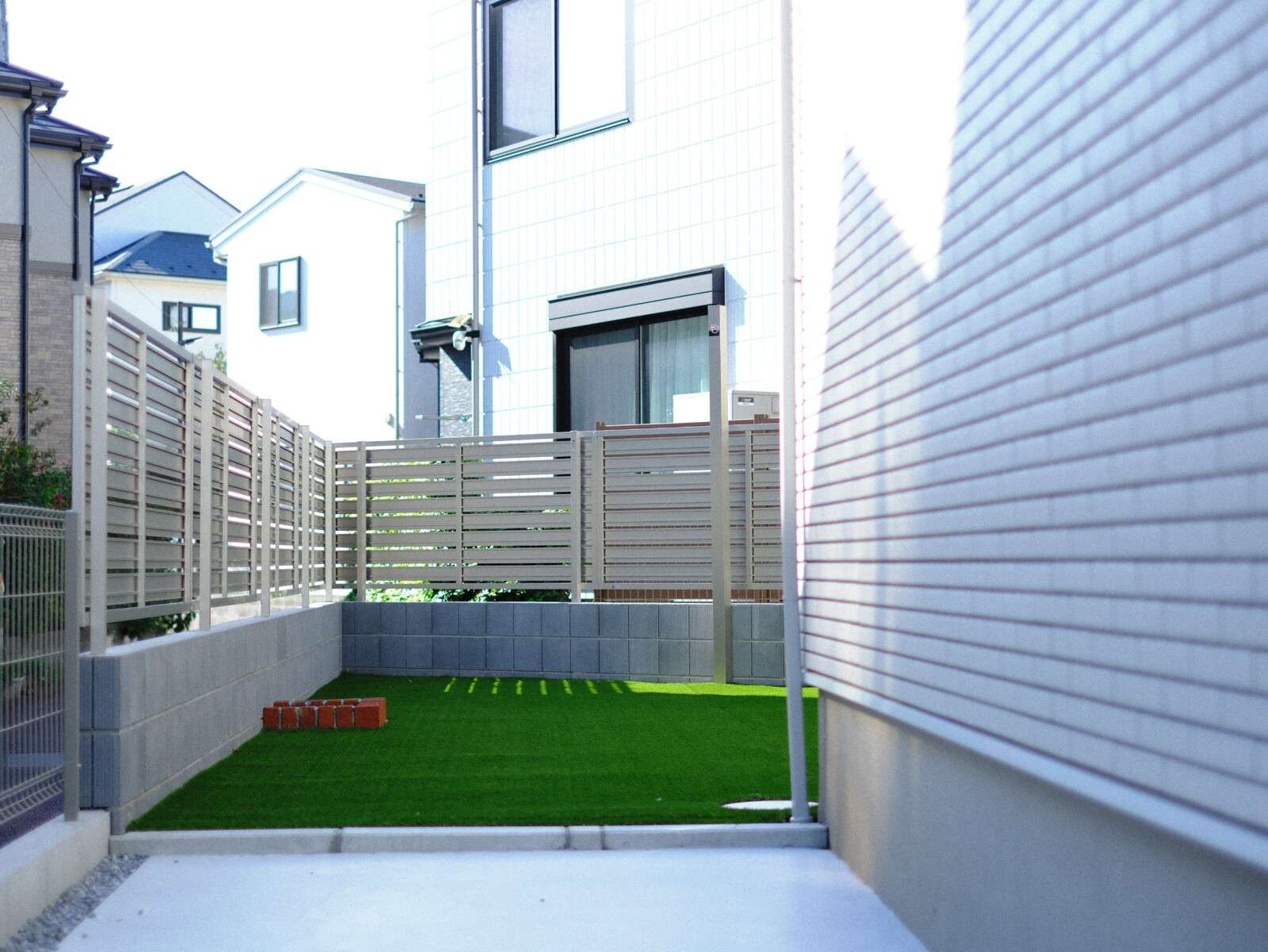 オリジナル物干しポールを設置した人工芝の庭。機能性とデザインを両立した庭空間