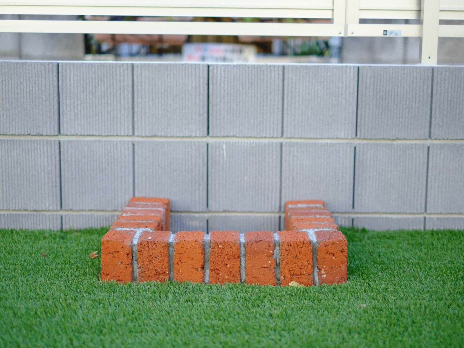 レンガ花壇と記念樹がある人工芝の庭。目隠しフェンスでプライバシーを確保した草加市の新築外構