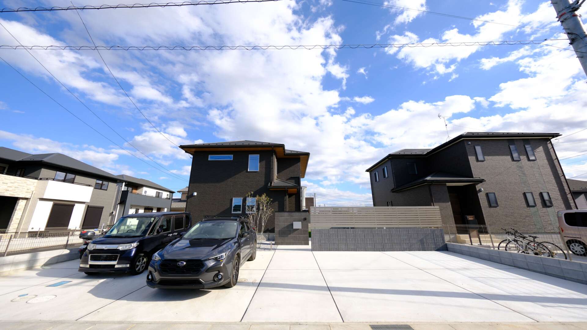 春日部市の新築外構全景。大判タイル門柱と目隠しフェンスが特徴のメリハリをつけたセミクローズ外構。