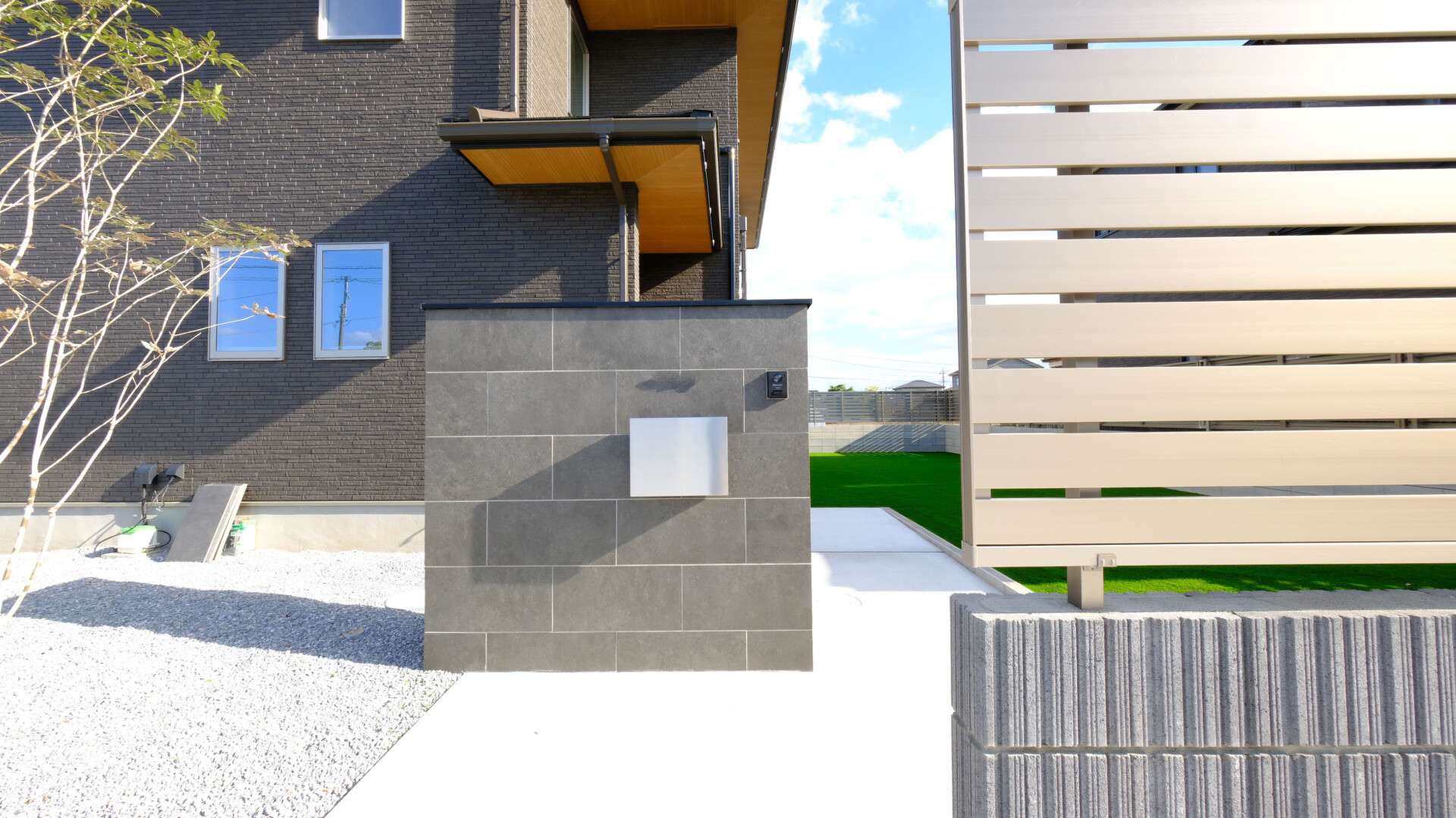 施工完了後の外構ファサード全景。コストを抑えるため砕石を敷いたエリアも見える。