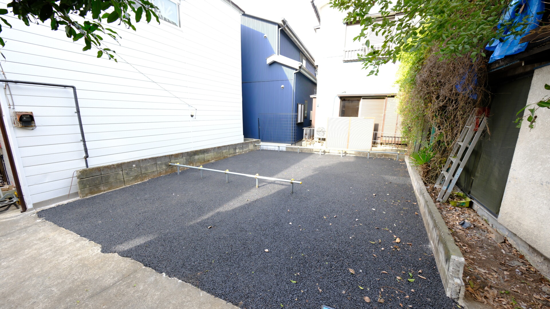 全面を黒いアスファルトで舗装し、単管パイプで区画を分けた清潔感のあるバイク置き場。