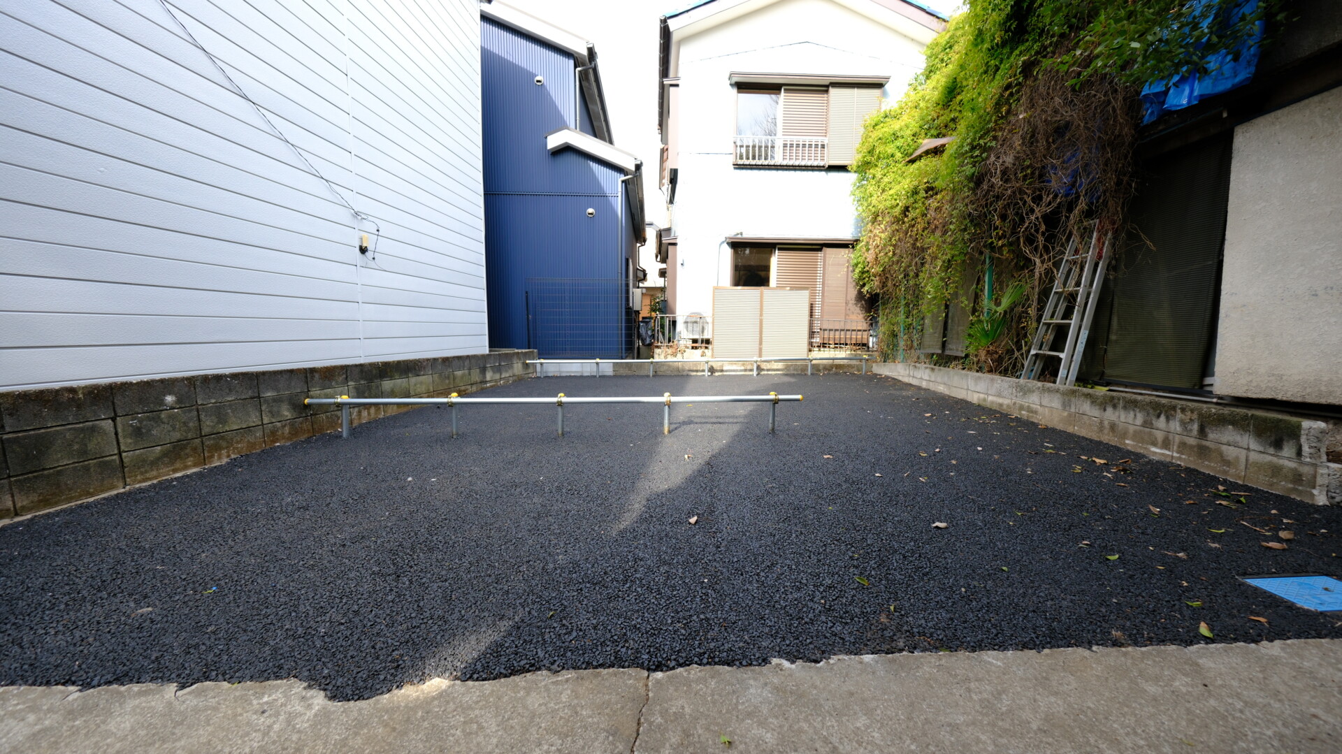 全面を黒いアスファルトで舗装し、単管パイプで区画を分けた清潔感のあるバイク置き場全景１