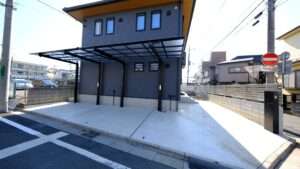 川口市の新築住宅 外構完成写真。台形カーポートと宅配ボックスが映る全景。