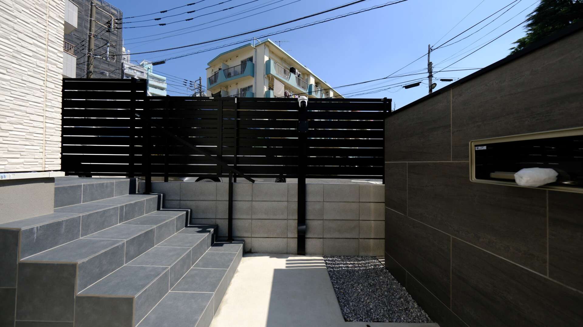 高さ1.6mの目隠しフェンス。隣接する駐車場からの視線をカットしつつ圧迫感を抑えた設計。