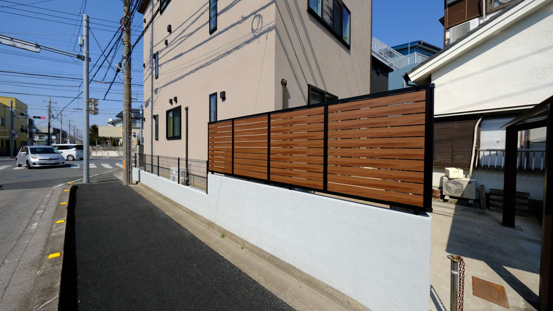 道路側から見た目隠しフェンス、木目調で建物と調和