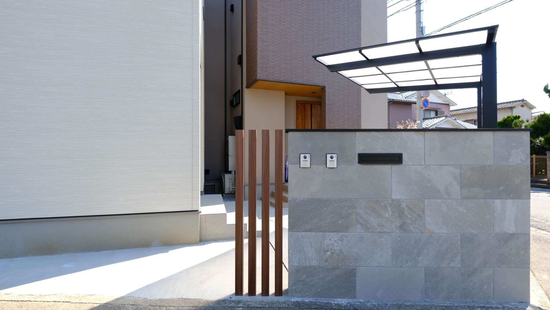 大判タイル門柱とポスト・表札が一体化した塀とアクセントの木調アルミ柱