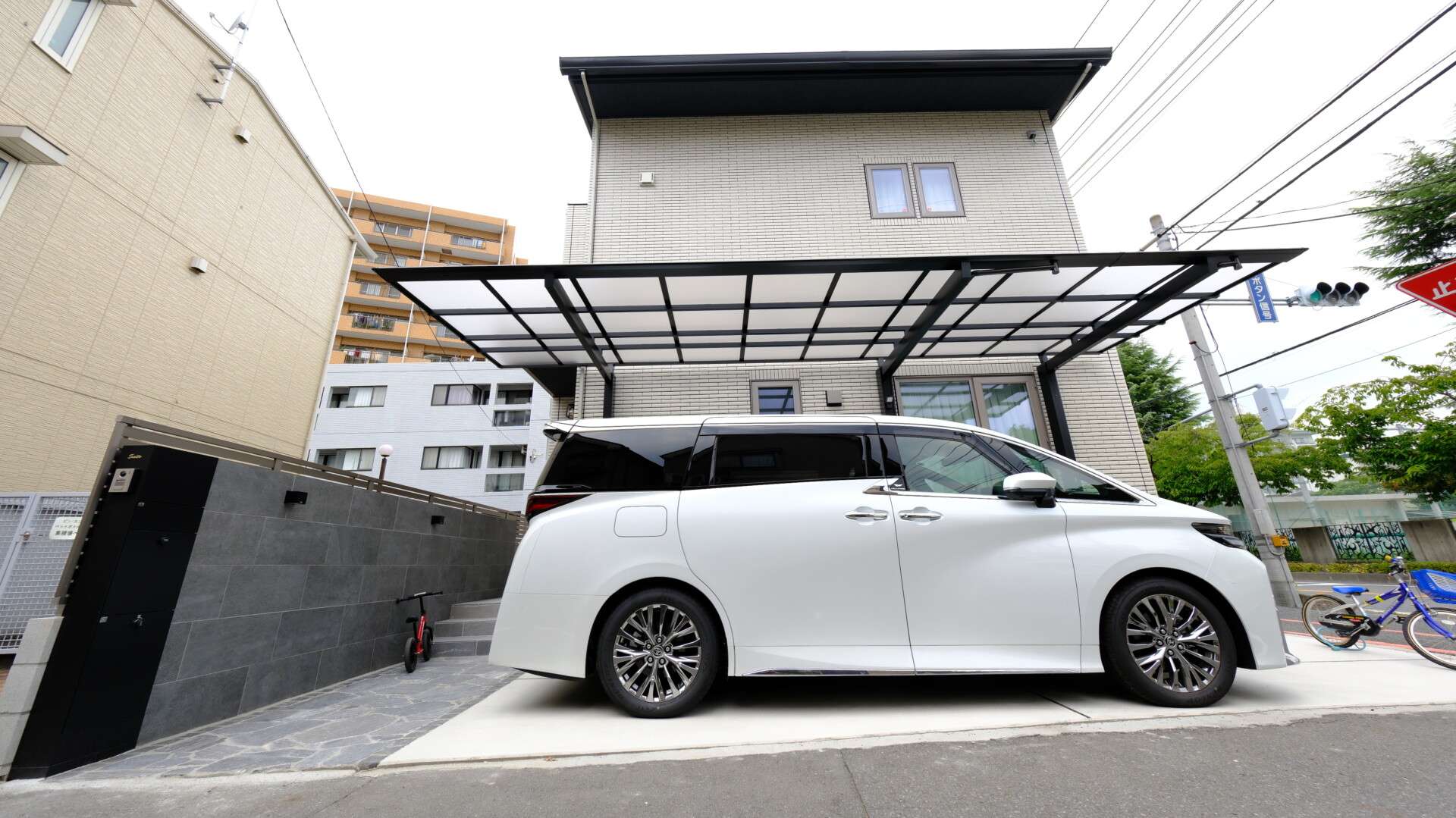 大判タイルを使用した重厚感のある門塀と機能門柱が映える玄関まわり、逆勾配カーポートと広々とした駐車スペースの外構全景