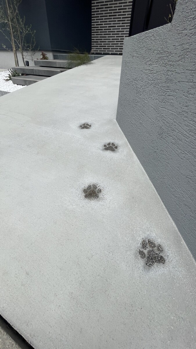 アプローチのコンクリートに施された、遊び心あふれる可愛い愛犬の足跡スタンプ