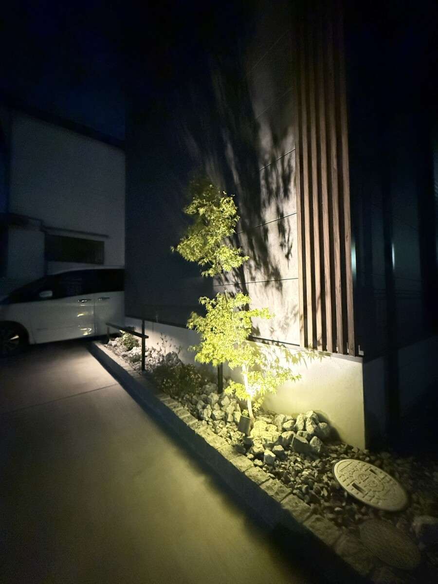 照明が当たるフェンスと花壇、夜の雰囲気を演出する外構