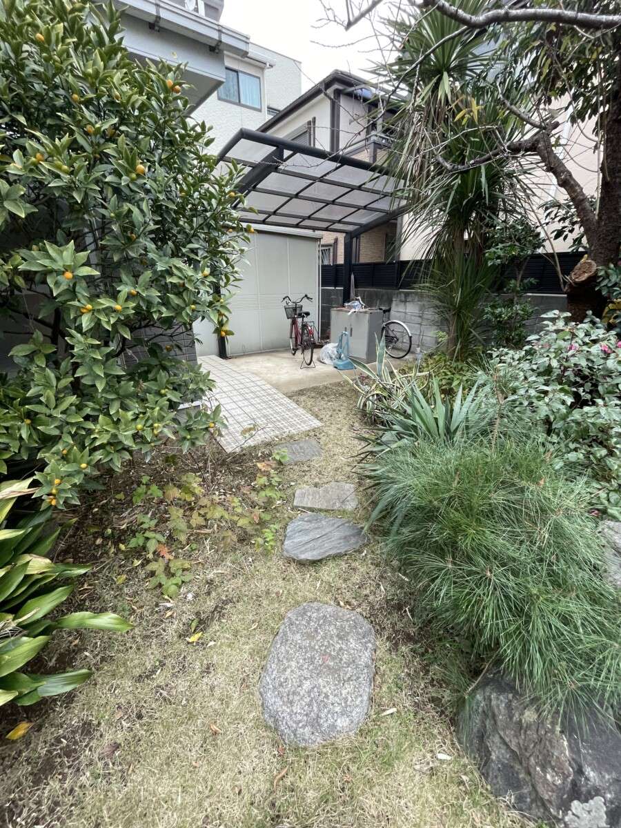 剪定が難しくなった植栽と飛び石のある自転車置き場（リフォーム前）