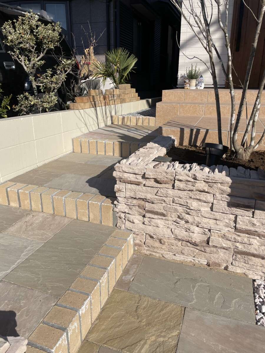 植栽や石材を活用したナチュラルな玄関アプローチ。シンボルツリーと調和した落ち着いたデザイン。