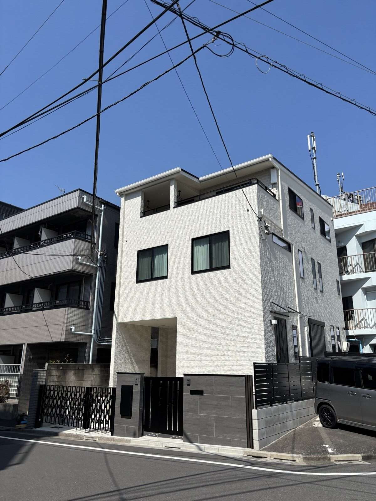 門まわりの全景。新築クローズ外構の門まわり全景。親子門扉と大判タイル門柱、スマート宅配ボックスが配置された防犯性の高いエントランス。