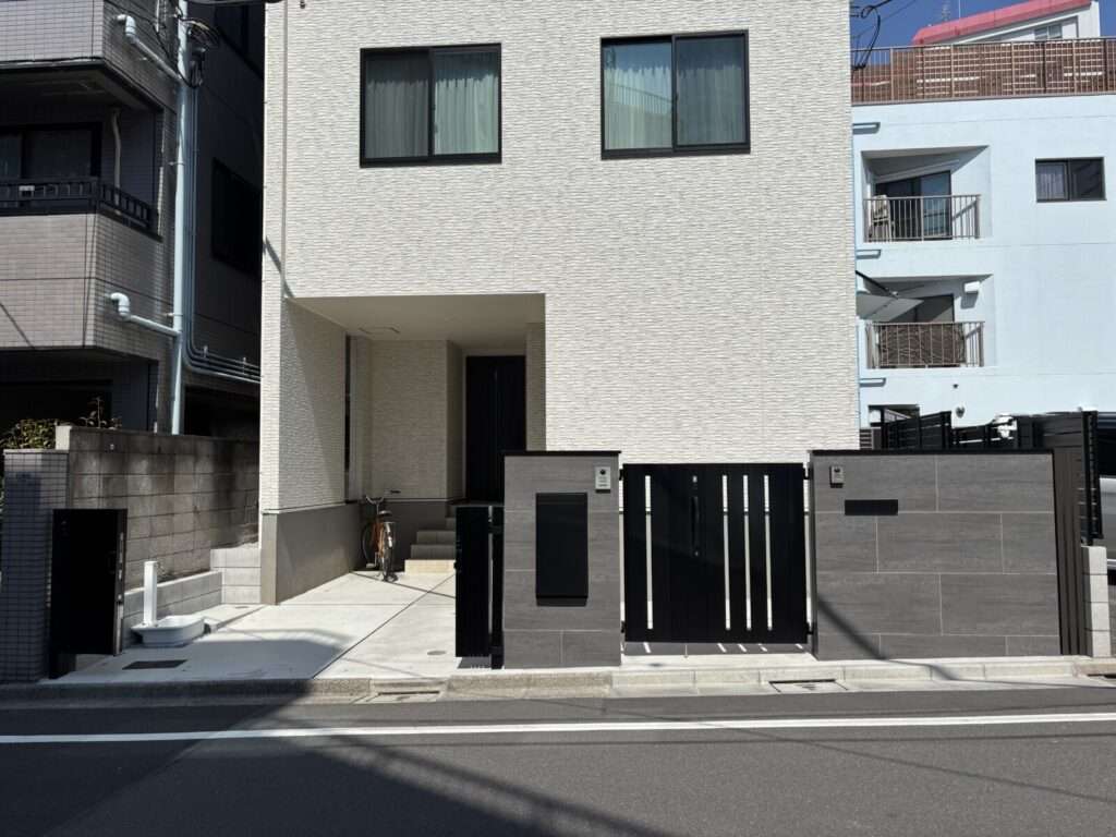 LIXIL製の電気錠付き親子門扉。高尺で外から内鍵に手が届かない設計。傾斜地に対応した伸縮門扉「アルシャインHG」。車庫前の安全対策として設置。