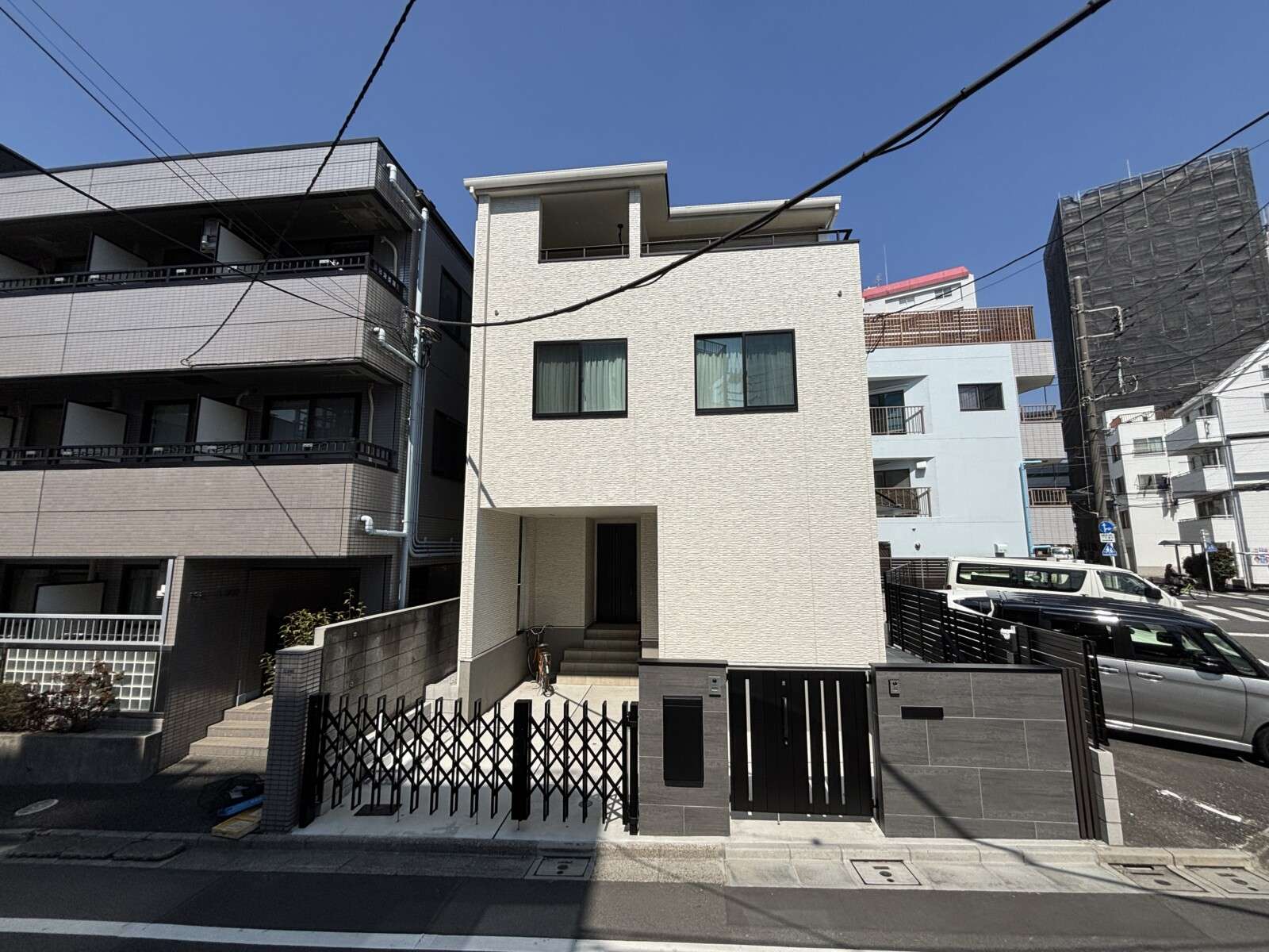 新築クローズ外構の門まわり全景。親子門扉と大判タイル門柱、スマート宅配ボックスが配置された防犯性の高いエントランス。