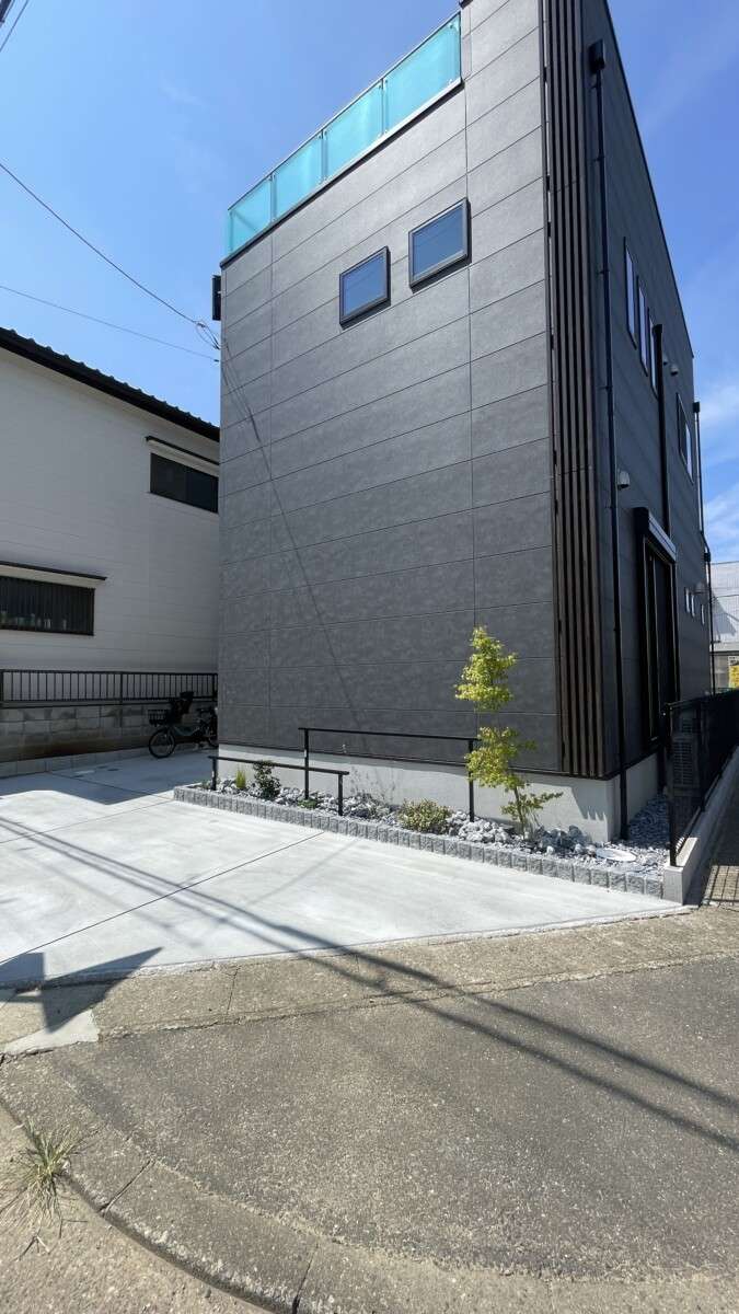 ピンコロで縁取られた花壇と緑が映えるアプローチ