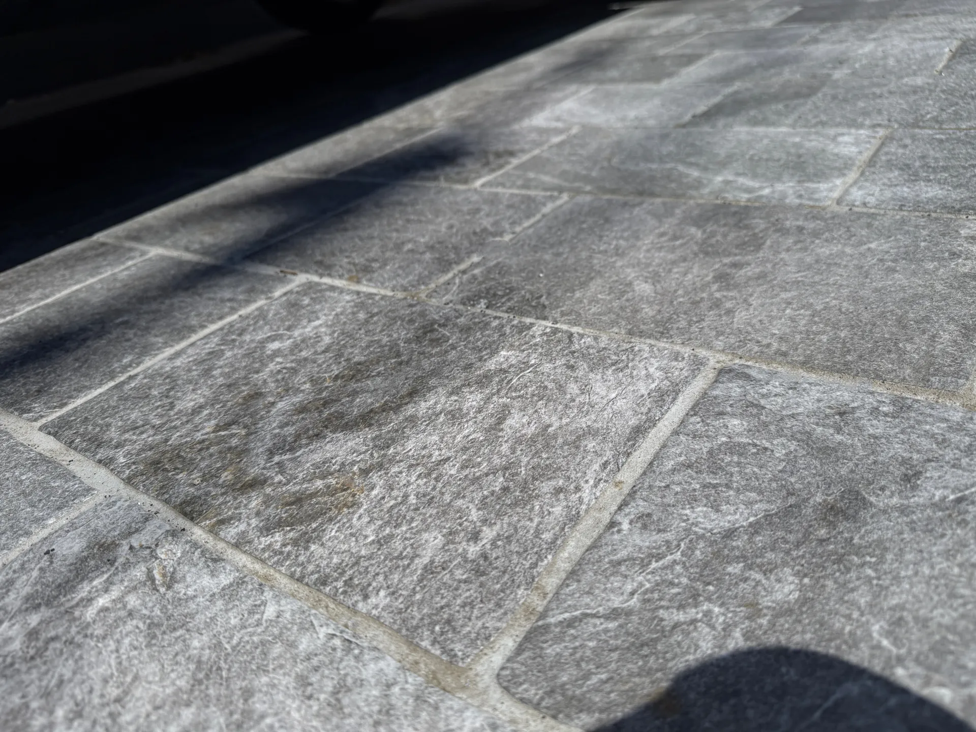 ミラタップ製の20mm厚・自然石調タイル。車両の乗り入れにも耐える強度と高級感を兼ね備えた足元。