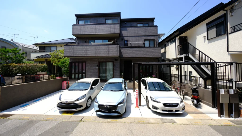 東川口・セキスイハイム二世帯新築外構の全景。リビエラタイル張りのアプローチ階段と土間コンクリートの駐車スペースが整然と並ぶ仕上がり
