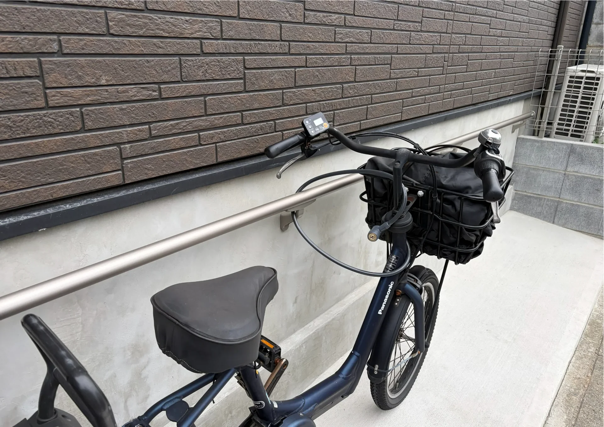 建物基礎を利用して設置した壁付け手すりに、鍵をかけて固定された自転車(さいたま市)