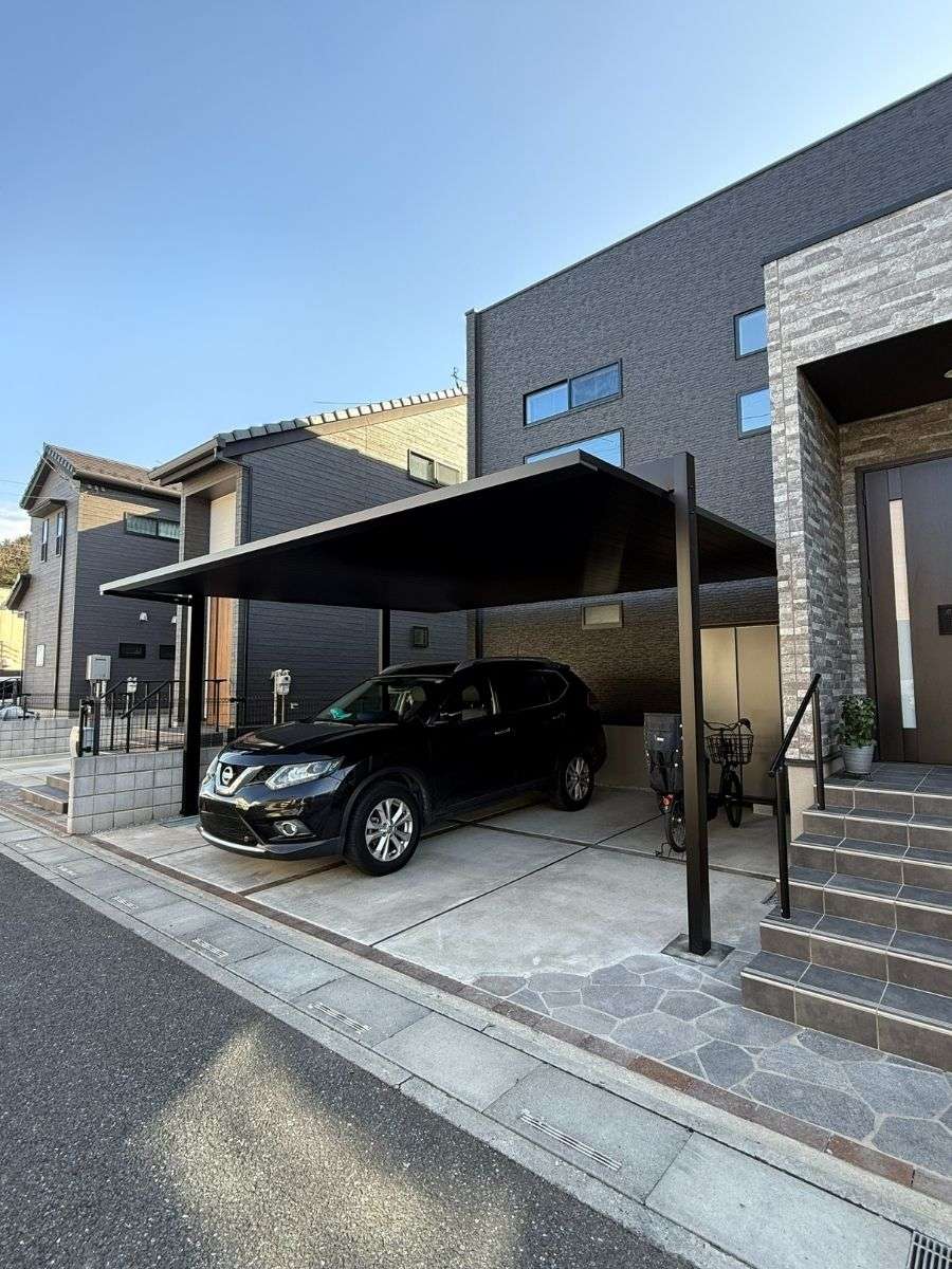 建物と並んで配置された黒いFⅡカーポートの柱と屋根構造が見える角度